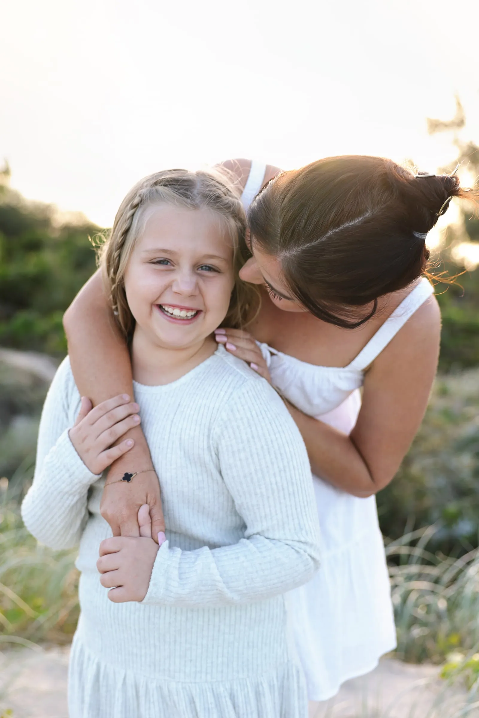 Mum kissing her daughter's cheek among the dunes