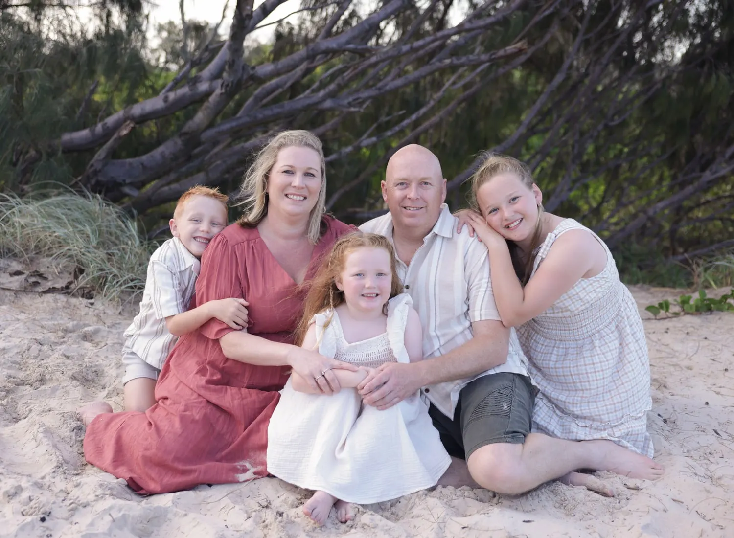 Family of five sitting together on the sand