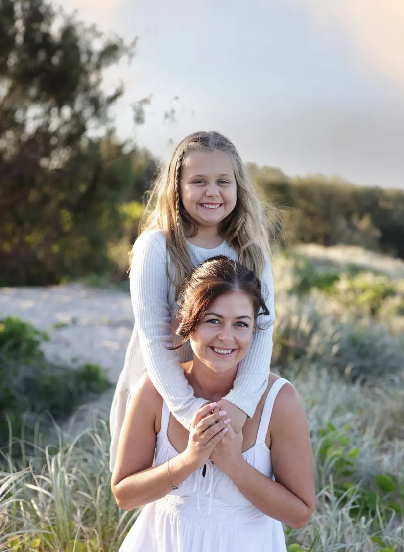 Daughter hugging her mum from behind in the dunes