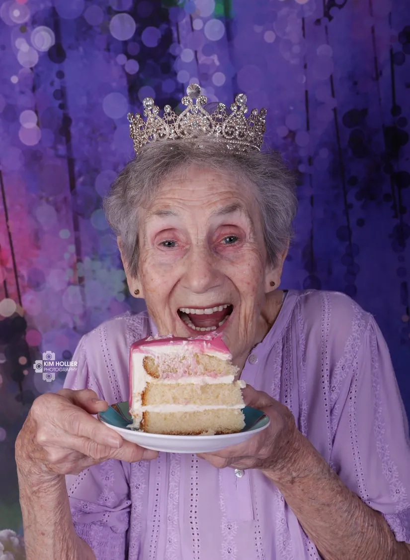 Birthday girl turning 92, in a tiara, holding a slice of cake