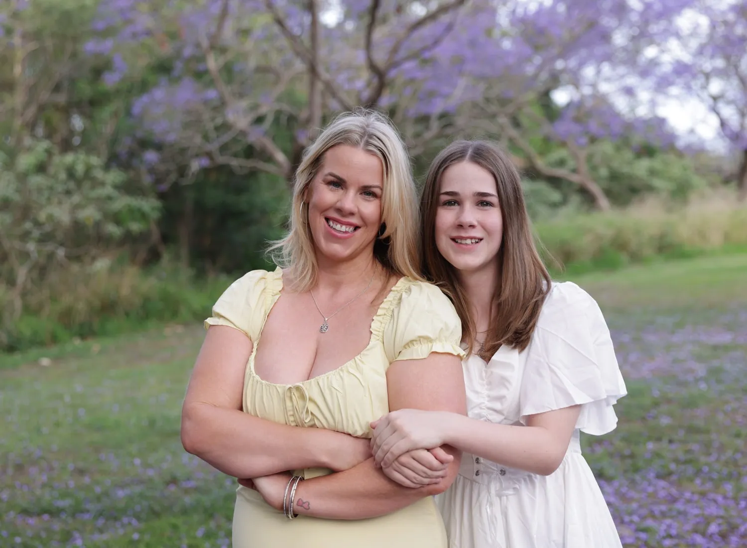 Mum and teenage daughter hugging under a jacaranda