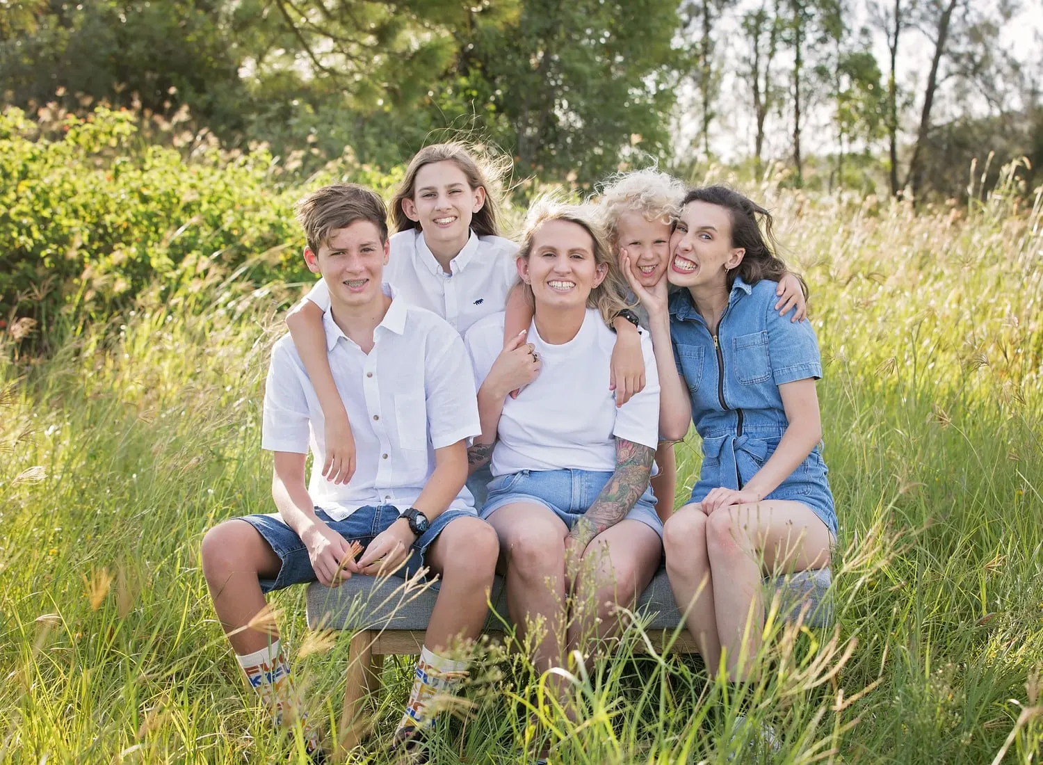 Four siblings sitting together in long grass