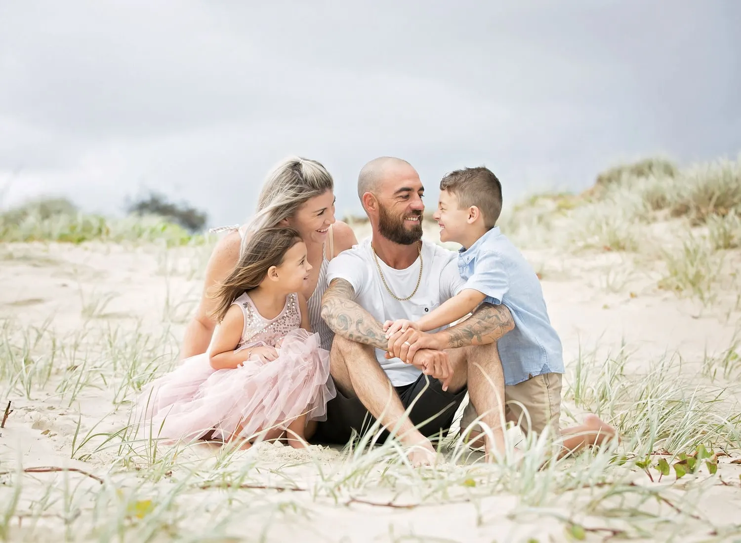Dad cuddling his son and daughter in the dunes