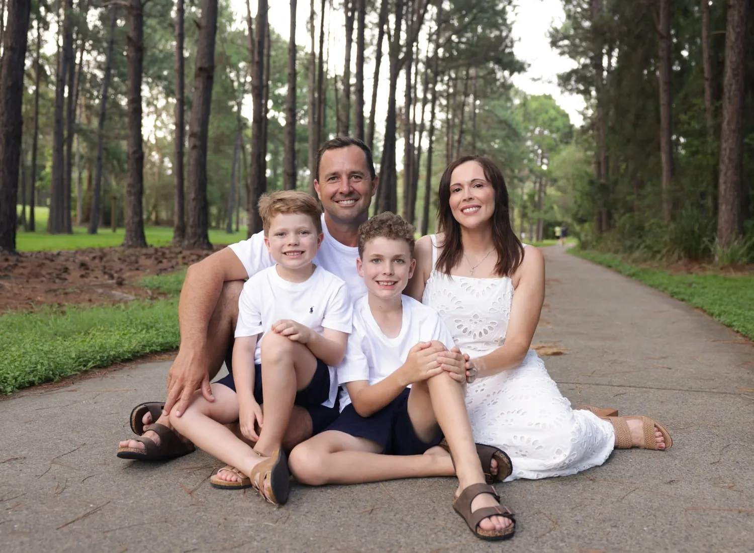 Family of four sitting on a path among tall pines