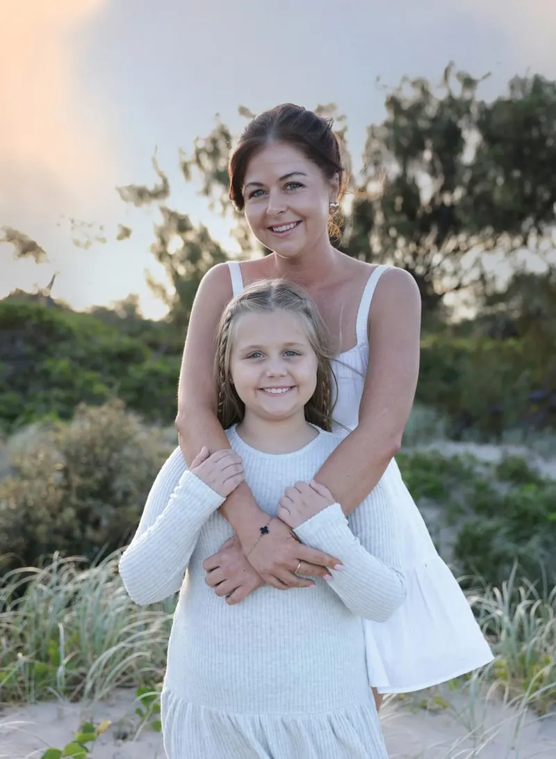 Daughter hugging her mum from behind in the dunes at dusk