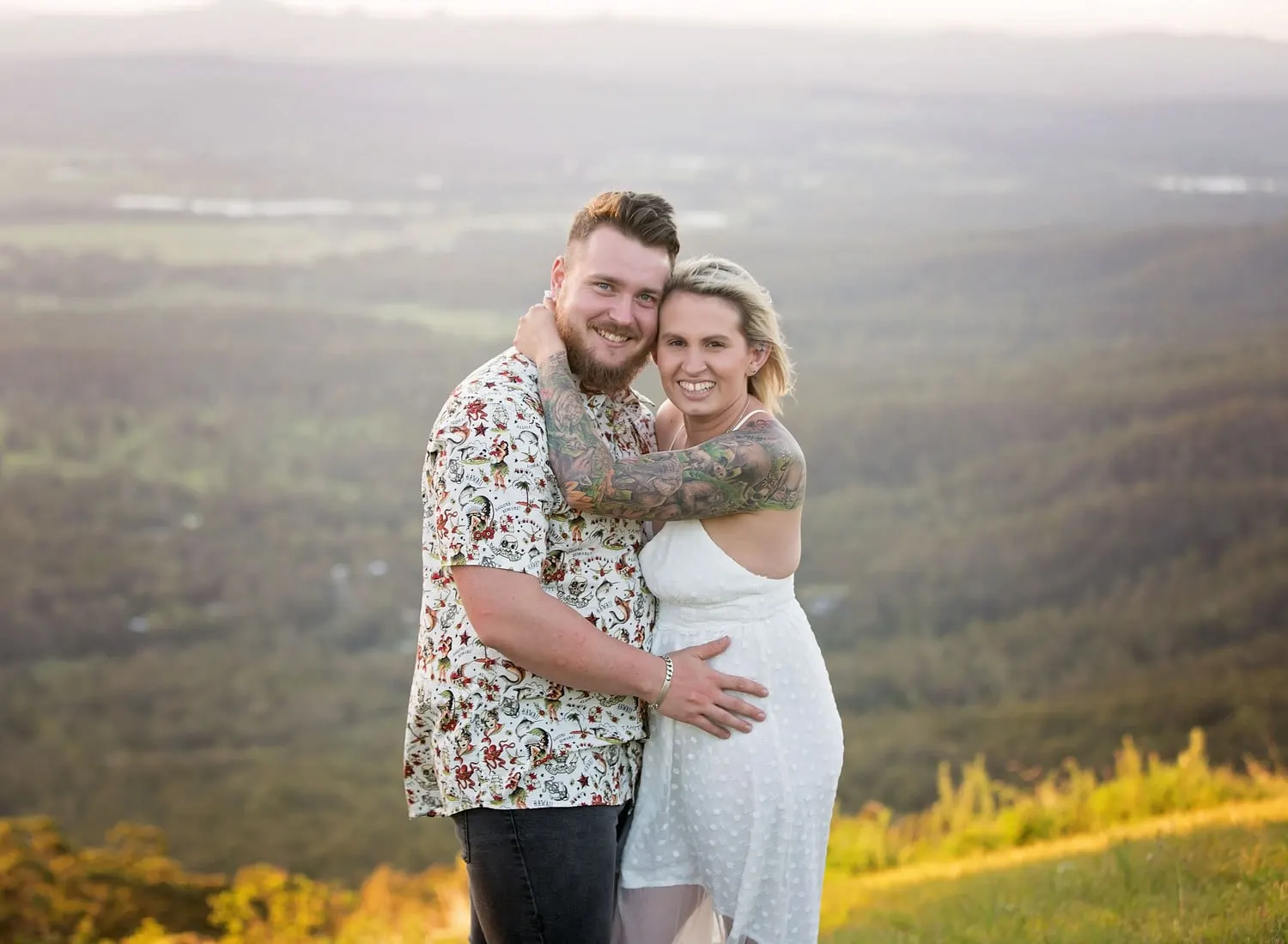 Couple hugging at a lookout with the valley behind