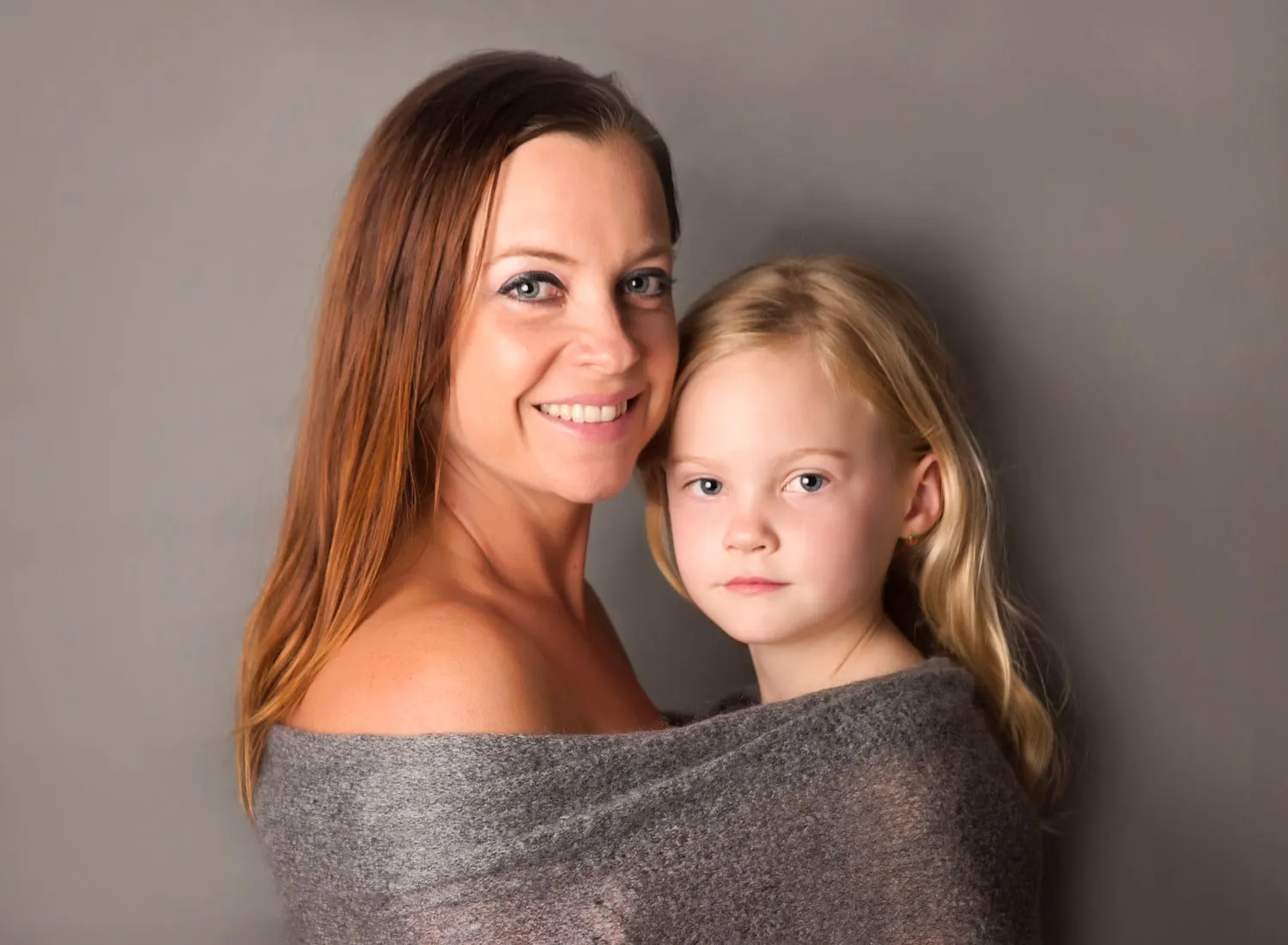 Mum and daughter cheek to cheek in a grey wrap in the studio