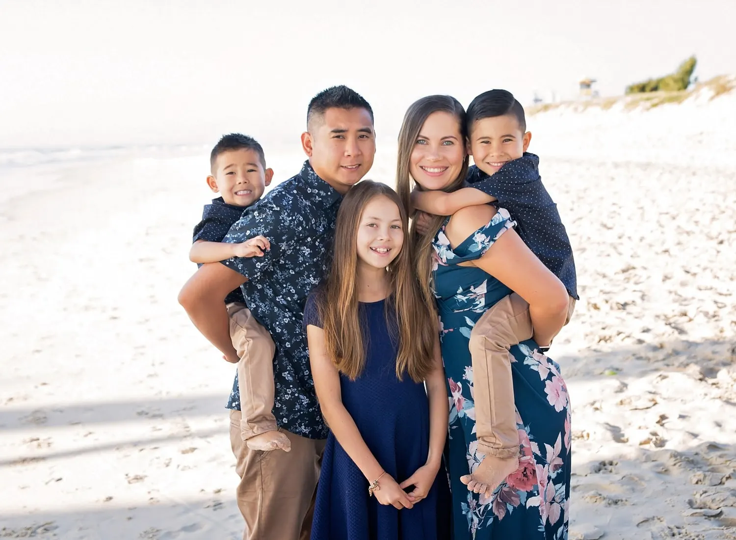 Family of five on the beach, boys on their parents' backs