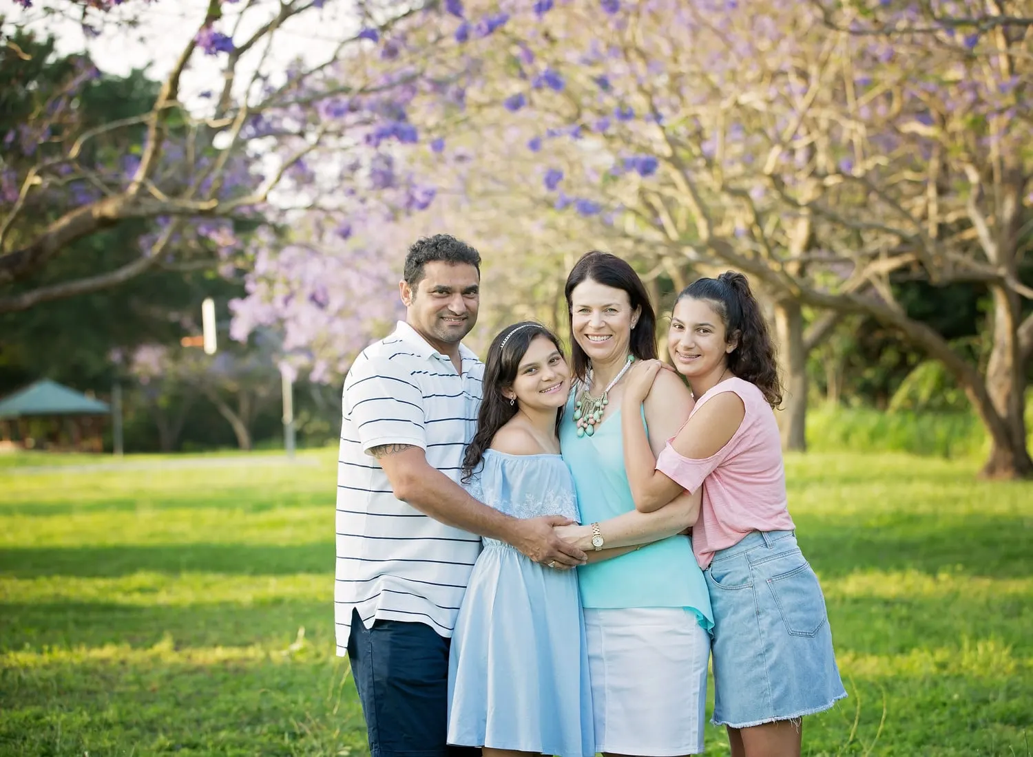 Family of four under a jacaranda in a park