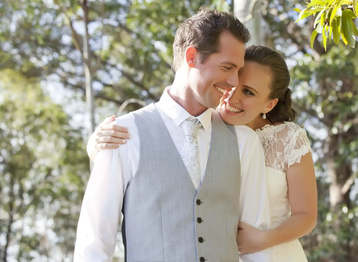 Bride and groom cheek to cheek among the trees