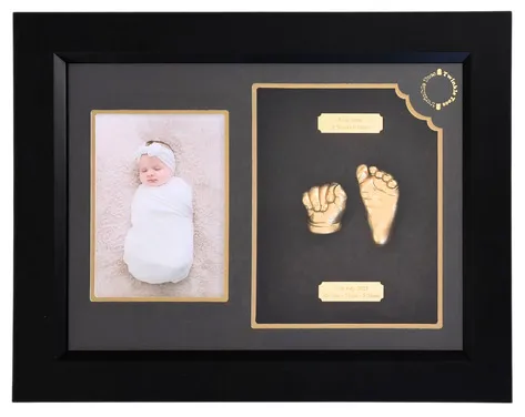 Gold newborn hand and foot with a photo of the swaddled baby, in a black frame