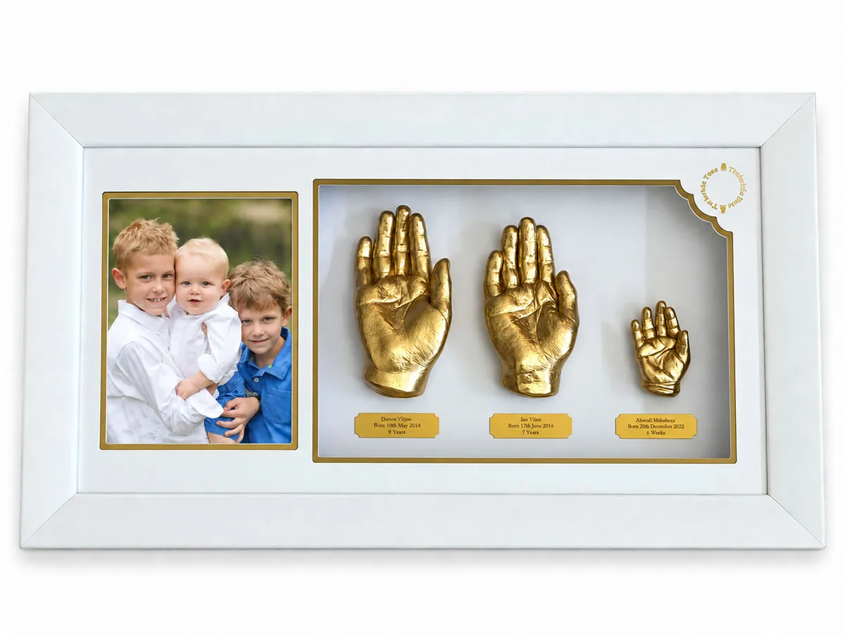 Three children's gold hand castings with a photo of the brothers, in a white frame